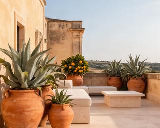 Terrazza privata a Modica con vasi in terracotta, agavi e sedute in pietra